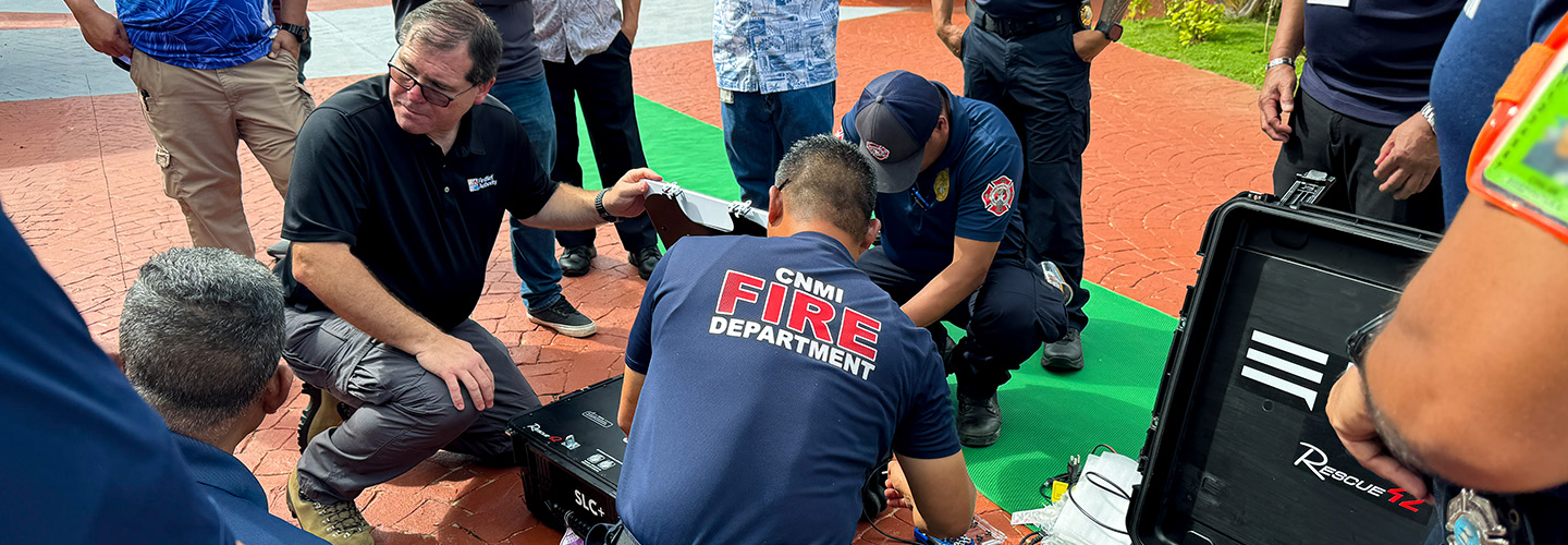 A FirstNet Authority staff member helps CNMI Fire Department learn how to use a MiniCRD.