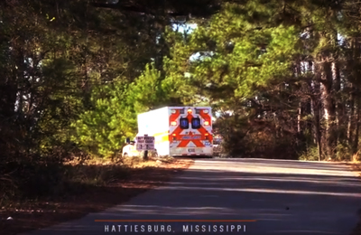 An ambulance drives down a small road on a sunny day. An ambulance drives down a small road on a sunny day.