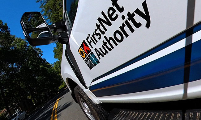 A truck bearing the FirstNet Authority logo drives down the road