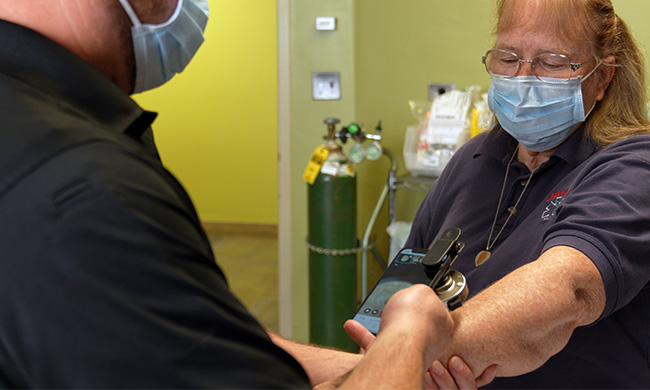 A clinic staff member uses an app on a FirstNet device to help a patient