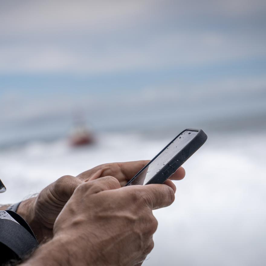 A fire chief holds a FirstNet enabled phone on board a boat