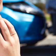 A woman making a phone call in front of a fender bender. A woman making a phone call in front of a fender bender.