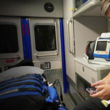 Public Safety First podcast logo; EMS official sits in ambulance and holds smartphone in hand