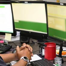 An emergency dispatcher sits in front of an emergency response system with his headset on. An emergency dispatcher sits in front of an emergency response system with his headset on.