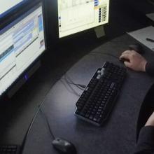Male dispather viewing a bank of monitors at his desk
