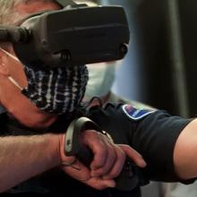 First responder wearing virtual reality glasses and holding controllers and gesticulates forward. First responder wearing virtual reality glasses and holding controllers and gesticulates forward.