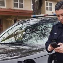 San Antonio Police officer near his car looking at a cell phone
