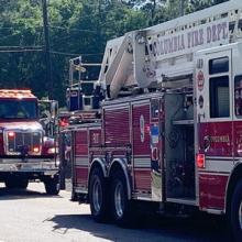 Three fire engines on the street with two fireman standing in front of one