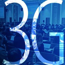 3GPP shifts focus toward 6G while continuing work on 5G-advanced A group of people dressed in business attire taking notes on electronic devices while seated in a large conference room with three oversized presentation screens at the 3GPP 6G workshop; “3GPP”