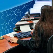 Tennessee leads nation in statewide adoption of FirstNet for 9-1-1 Cell tower; outline of the state of Tennessee; a 9-1-1 telecommunicator at her workstation