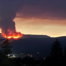 From daily operations to wildfires: How a rural Colorado fire district keeps connected The Derby Fire burning on a distant mountain obscuring most of the sky with smoke while clouds in background are illuminated by the fire.
