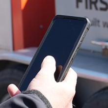 Police officer using a FirstNet enabled smartphone in front of a FirstNet SatCOLT