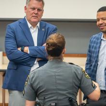 FirstNet Authority staff and Coverage Enhancement Workshop participants, including a uniformed law enforcement officer, stand in a circle speaking
