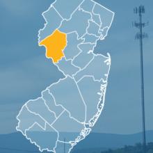 The state of New Jersey, with outlined county borders; a cell tower.