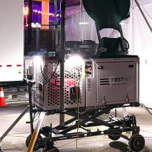 A FirstNet Compact Rapid Deployable set up near medical tents at the Electric Daisy Carnival. Trailer, wheelchair, side-by-side vehicle, and orange cones. 