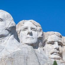 An emergency management office’s secret to staying connected, even at Mount Rushmore Framed on either side by tree branches, Mount Rushmore from below on a clear day with no clouds.