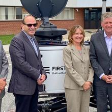 Rhode Island state government, emergency management, FirstNet Authority, and AT&T personnel stand in front of a portable cell site known as a Compact Rapid Deployable.