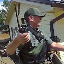 In the path of Hurricane Helene: FirstNet aids responders during response and recovery A first responder in tactical gear and holding a radio uses a pole and rope to assist a person through severe floodwaters outside a damaged home; Debris and muddy water surround the homes