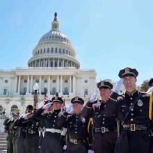 Nine police officers salute with the capitol building behind them during National Police Week 2017 in Washington DC. 