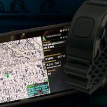 Smartphone displaying mapping location; wrist wearable device; background of firefighter uniforms hanging in a row. 