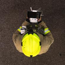 Aerial view of a firefighter wearing a helmet using a drone next to a firetruck 