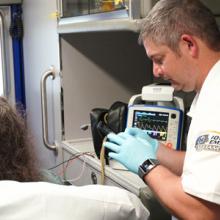 Emergency medical services personnel tend to a patient in an ambulance. 