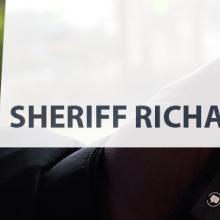 On left, headshot of Sheriff Richard Stanek in uniform, on right, a hand holds a FirstNet device with an app on it
