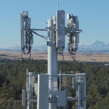 Cellular tower with forest and mountain landscape in backdrop