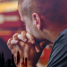 First responder somberly looking away; silhouette of New York City skyline with World Trade Center tower remembrance silhouettes