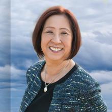  A cell tower against the backdrop of clouds with a headshot of a woman, Teri Takai. 