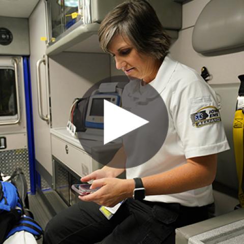 An EMS technician from the West Des Moines EMS team uses a smartphone in the back of an ambulance