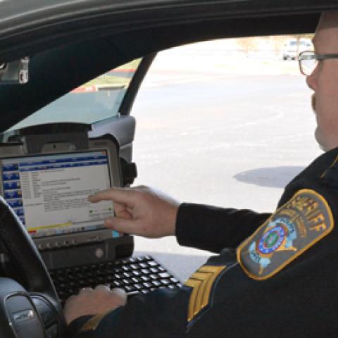 A Brazos County Sheriff's Department officer looks at a screen inside of his patrol car