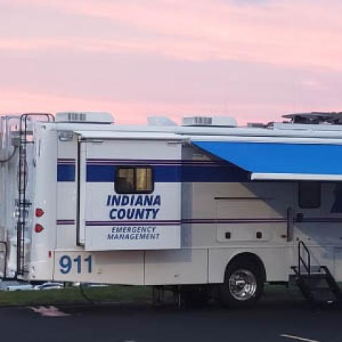 An Indiana County Emergency Management vehicle sits in a parking lot at sunset.