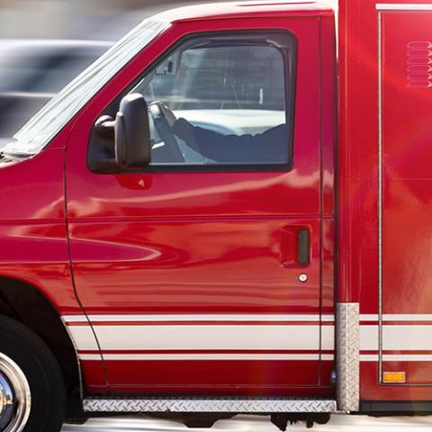Red ambulance in motion with blurred road in background.