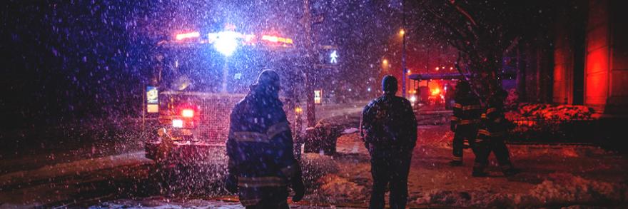 Firefighter standing by fire engine at snow covered city street