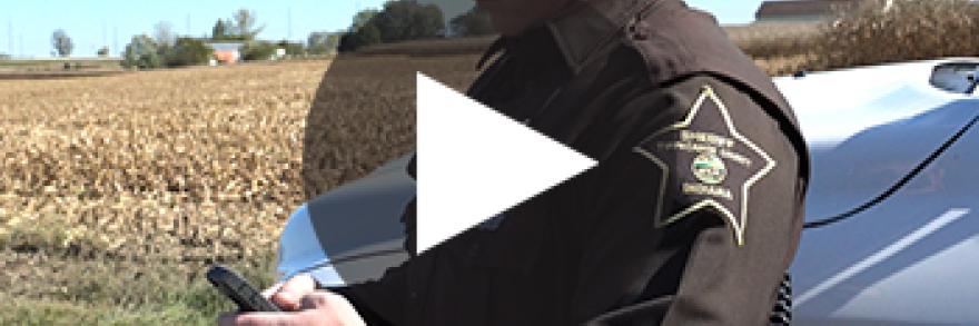 An Indiana responder standing near his vehicle works on a smartphone