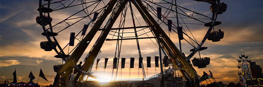 A Ferris wheel backlit by the sunset.