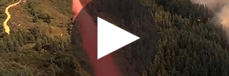 An airplane drops fire retardant on a wildfire