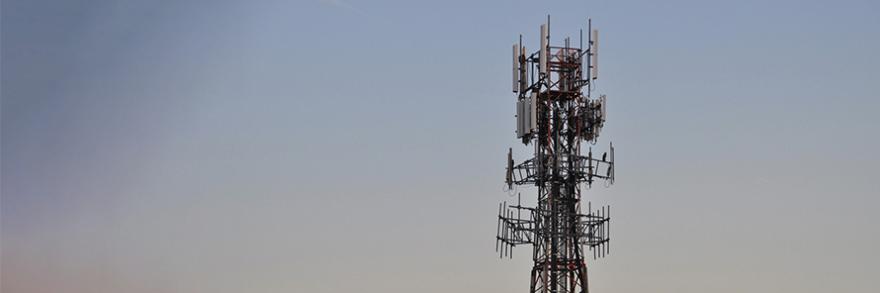 A cell tower and blue sky with wispy cloud