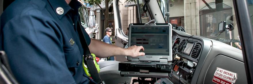 A paramedic using a laptop in the front seat of an ambulance