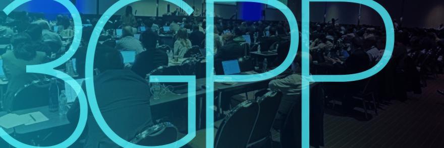 A large group of people dressed in business attire seated at conference tables while taking notes on electronic devices at a 3GPP plenary session in September 2024; "3GPP"   