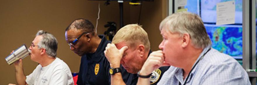 Pictured left to right sitting at a table with displays showing maps behind them: Gainesville (FL) Fire Chief Jeff Lane; Police Chief Tony Jones; Asst. Police Chief Terry Pierce; and Public Works Director Phil Mann.