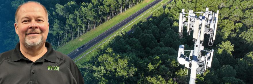 In the background, a rural road cuts through a dense forest with a cell tower rising above the treetops; on the left, West Virginia Department of Transportation Assistant Secretary Scott Eplin smiles.