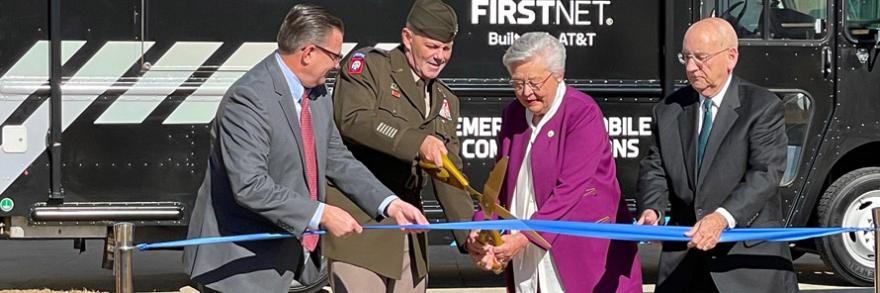 Deputy Commanding General of Army Materiel Command Lieutenant General Donnie Walker cuts a ribbon held by FirstNet Authority Board member Chief Richard Carrizzo, Alabama Governor Kay Ivey, and AT&T Alabama President Wayne Hutchens in front of a FirstNet Emergency Mobile Communications truck.