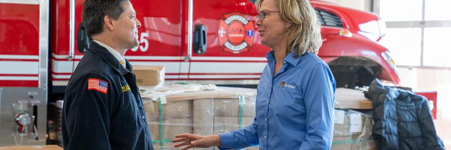 Boulder Fire-Rescue Chief Michael Calderazzo and FirstNet Authority Senior Public Safety Advisor Tracey Murdock stand talking in front of a fire truck