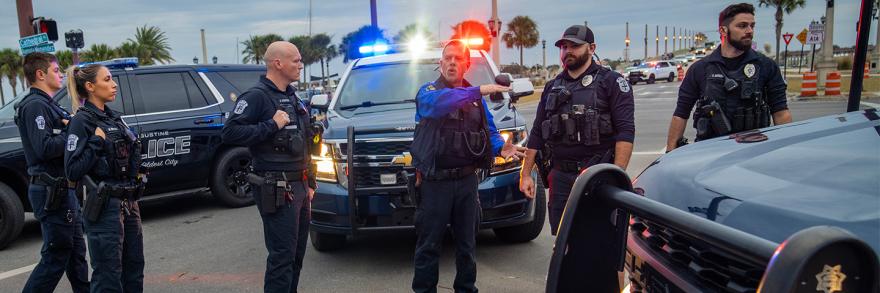 Six police officers talking in front of three police vehicles at an intersection in St. Augustine, Florida  