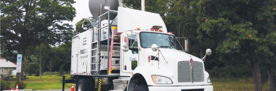 A FirstNet Satellite Cell on Light Truck (SatCOLT) is parked in a rural area and set up to provide a FirstNet LTE connection to support public safety operations.