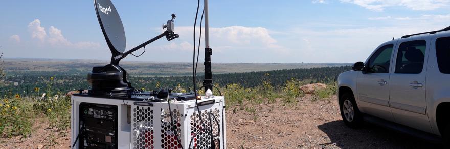 A FirstNet Compact Rapid Deployable on top of hill in Colorado in a rural area, the SUV that carried the CRD to the location is nearby