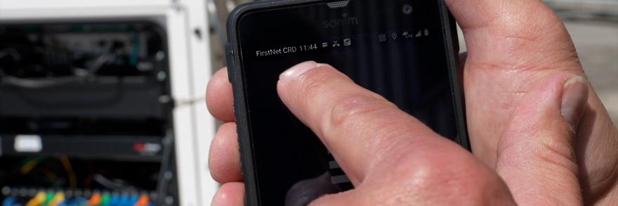 A first responder using a smart phone that is connected to the internet via a FirstNet Compact Rapid Deployable