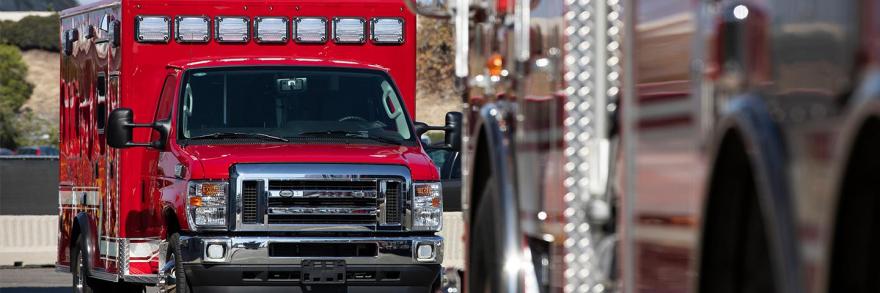 A red ambulance parked behind another public safety vehicle